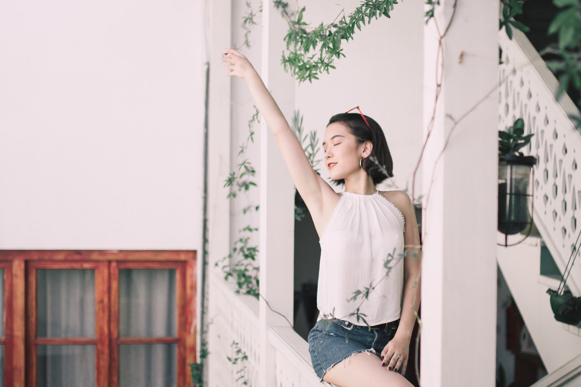 Happy woman is sitting on the stairs, raising her right hand